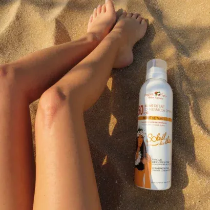Jambe sur la plage avec un flacon de brume solaire