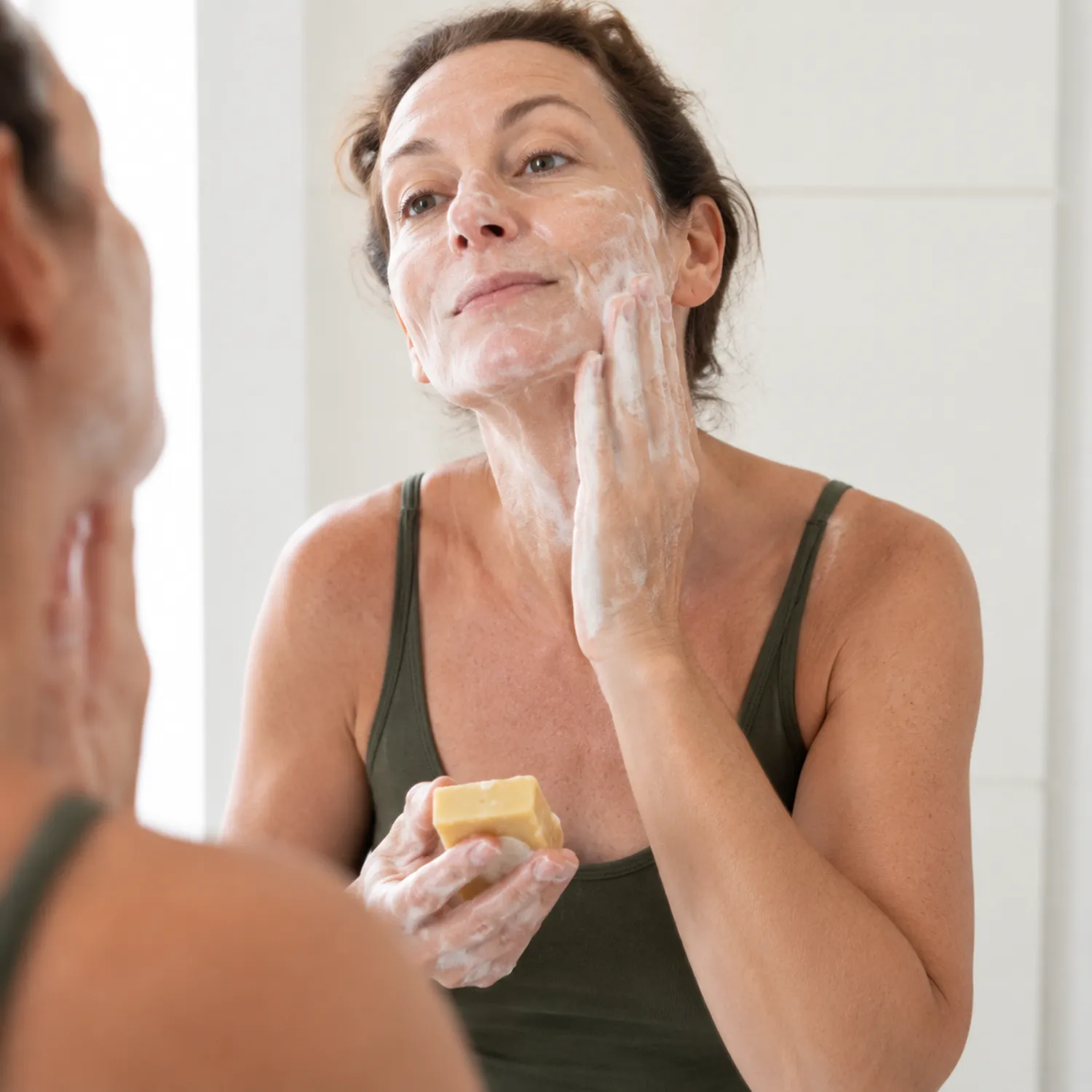 Femme mature appliquant savon bio anti-âge Louise émoi sur visage