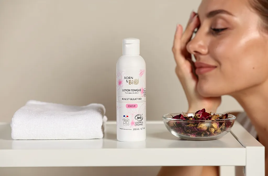 Huilier visage lumineux avec crème tonique bio, sur étagère blanche aux côtés d’une serviette et d’un bol de fleurs séchées, illustrant des routines beauté naturelle personnalisées.
